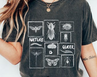 May include: Dark gray t-shirt with a white insect illustration design. The design includes various insects in white boxes, with the words "NATURE IS QUEER" in white text. The shirt has a vintage, worn look.