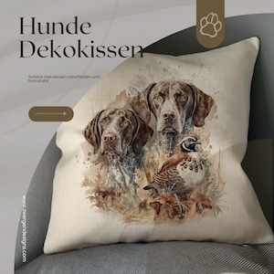 Könnte beinhalten: Ein dekoratives Kissen mit einer Illustration im Aquarellstil von zwei Hunden und einem Vogel. Die Hunde haben braunes und weiß geflecktes Fell. Das Kissen trägt die Aufschriften "Hunde Dekokissen" und "Schöne Dekokissen naturfarben und formstabil".