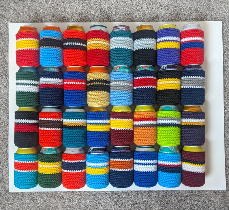 May include: A collection of 36 crocheted can coolers in various colors and patterns. The coolers are made with a variety of yarn colors, including red, blue, green, yellow, and white. Each cooler has a different pattern, including stripes, polka dots, and geometric designs.