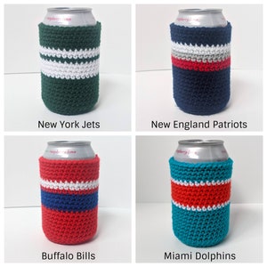 May include: Four crocheted can coolers in team colors. The coolers are green and white, navy blue and red, red and blue, and teal and orange. The coolers are labeled with the team names: New York Jets, New England Patriots, Buffalo Bills, and Miami Dolphins.