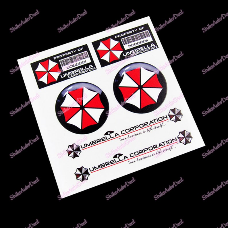 May include: Four black and white stickers with a red umbrella logo. The stickers feature the text "PROPERTY OF" and "UMBRELLA CORPORATION". Two of the stickers are round and have a 3D effect. The other two stickers are rectangular and have the text "our business is life itself..." below the logo.