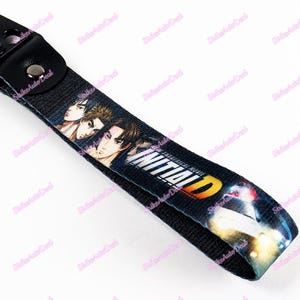 May include: Black and white key chain with a graphic of three anime characters and the text "Initial D: The Theatrical Movie".