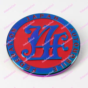 May include: A round, iridescent blue and red emblem with the text "JAPAN AUTOMOBILE FEDERATION" surrounding a stylised "74" logo.