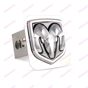 May include: Chrome plated metal hitch cover with a silver and black Ram logo. The logo features a ram's head with horns.