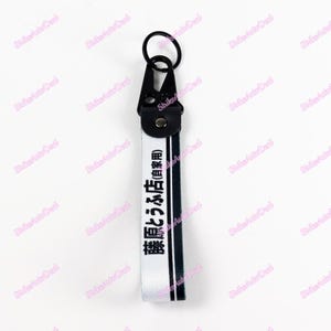 May include: A black and white keychain with the text "藤原とうふ店(自家用)" printed on it. The keychain has a black metal ring and a black clip.