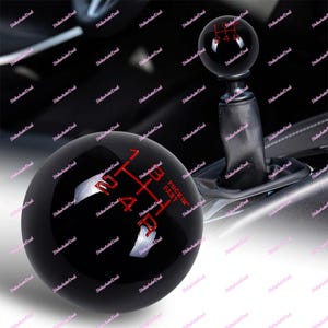 May include: Black shift knob with red gear numbers and the text "FUCKIN' FAST". The knob is round and glossy, with a leather boot visible below. The gear pattern is clearly marked for easy use.