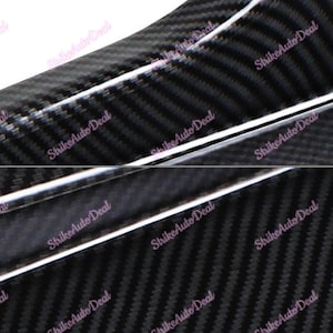 Puede incluir: Primer plano de una superficie texturizada de fibra de carbono negra con una franja plateada que la atraviesa. La superficie tiene un patrón repetitivo de líneas diagonales.