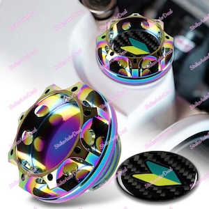 May include: Two iridescent oil fill caps with a black and green carbon fibre sticker with a chevron design.