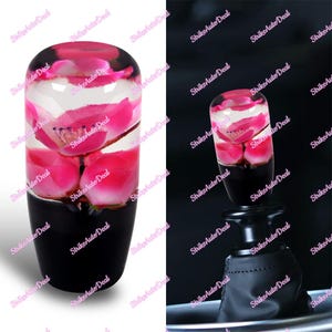 Pode incluir: Manípulo da alavanca de câmbio do carro com flores de lótus rosa encapsuladas em resina transparente. A base do manípulo é preta. Projetado para substituir o manípulo da alavanca de câmbio existente em um veículo.