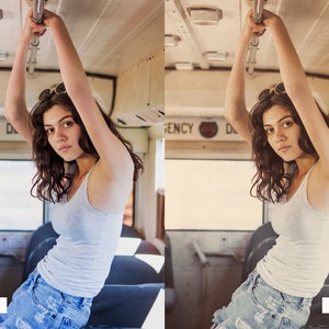 May include: A woman with long brown hair is wearing a white tank top and blue denim shorts. She is holding onto a metal bar on a bus. The word "EMERGENCY" is visible on the bus.