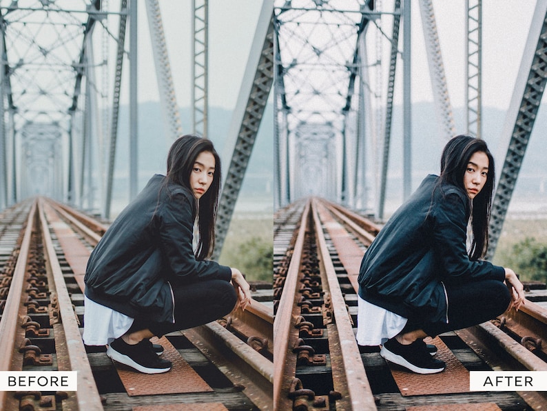 May include: A woman wearing a black jacket and black pants sits on a set of railroad tracks on a bridge. The bridge is made of metal and has a gray background.