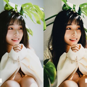 May include: A young person with long dark hair is wearing a white sweater and sitting with their hands clasped in their lap. The person is sitting in front of a green leafy plant.