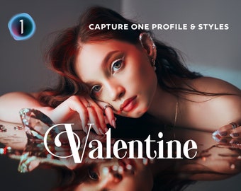 Puede incluir: Una mujer con cabello largo y oscuro está acostada sobre una superficie reflectante. Lleva un collar de oro y un anillo de diamantes en su dedo. La palabra "Valentine" está escrita en letras blancas sobre la superficie.