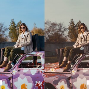 May include: A woman wearing sunglasses and a beige jacket sits on the roof of a pink car with white flowers painted on it. She is holding shopping bags.