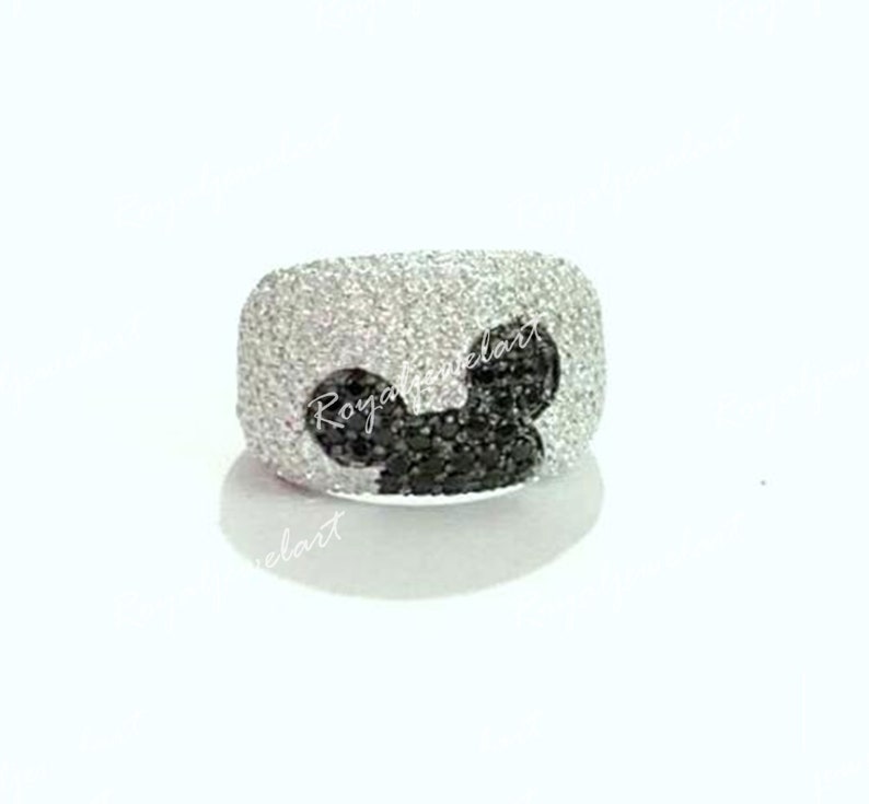K&ouml;nnte beinhalten: Ein silberner Ring mit einem schwarzen Diamanten-Mickey-Mouse-Design. Der Ring ist mit kleinen wei&szlig;en Diamanten besetzt.