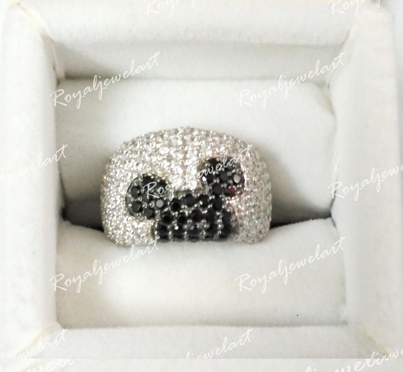 K&ouml;nnte beinhalten: Ein silberner Ring mit schwarzen und wei&szlig;en Steinen, die in einem Mickey-Mouse-Design eingefasst sind.