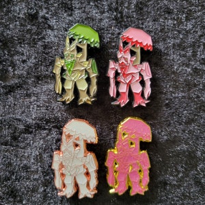 Pode incluir: Quatro pinos de esmalte com um design de robô geométrico com uma árvore no topo. Os robôs são de diferentes cores: verde, rosa, branco e dourado.