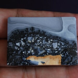 May include: A rectangular slab of polished gray, black, and tan agate with a swirling pattern. The stone has a natural, organic look.