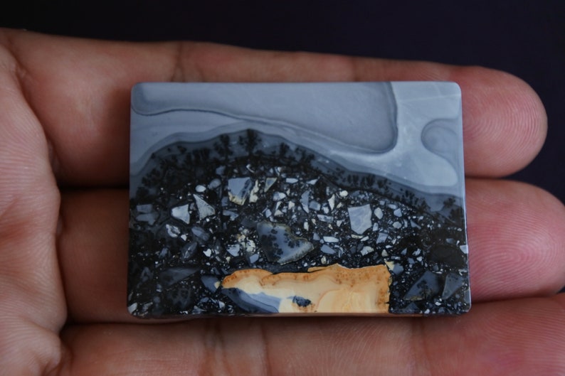 May include: A rectangular slab of polished gray, black, and tan agate with a swirling pattern. The stone has a natural, organic look.