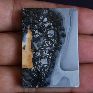 May include: A rectangular, polished stone with a gray, white, and black pattern. The stone has a brown, orange, and black section on the left side.