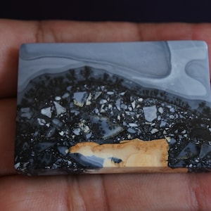 May include: A rectangular slab of polished agate with a swirling pattern of gray, black, and brown. The stone has a unique, marbled appearance.