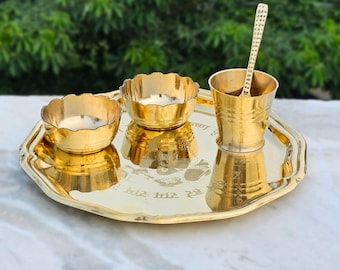 Puede incluir: Una bandeja de metal dorada con dos cuencos pequeños y una taza. La bandeja tiene una inscripción en hindi.