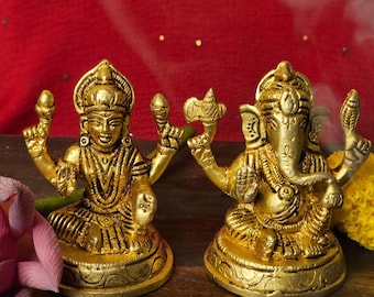 Peut inclure: Statues en métal doré de Lakshmi et Ganesha, divinités hindoues, assises sur une surface en bois. Les statues sont finement détaillées et présentent un design indien traditionnel.