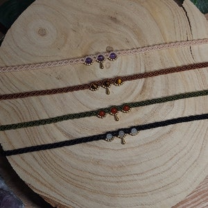 May include: Four layered necklaces with different coloured cords and gemstone accents. Each necklace has a gold pendant with a teardrop shape.