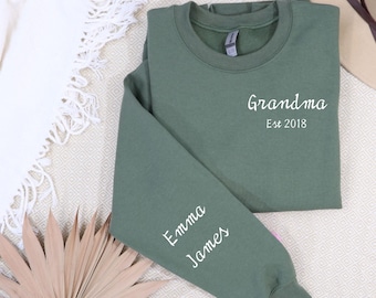 May include: A green sweatshirt with the text "Grandma Est 2018" on the front and the names "Emma James" on the sleeves.