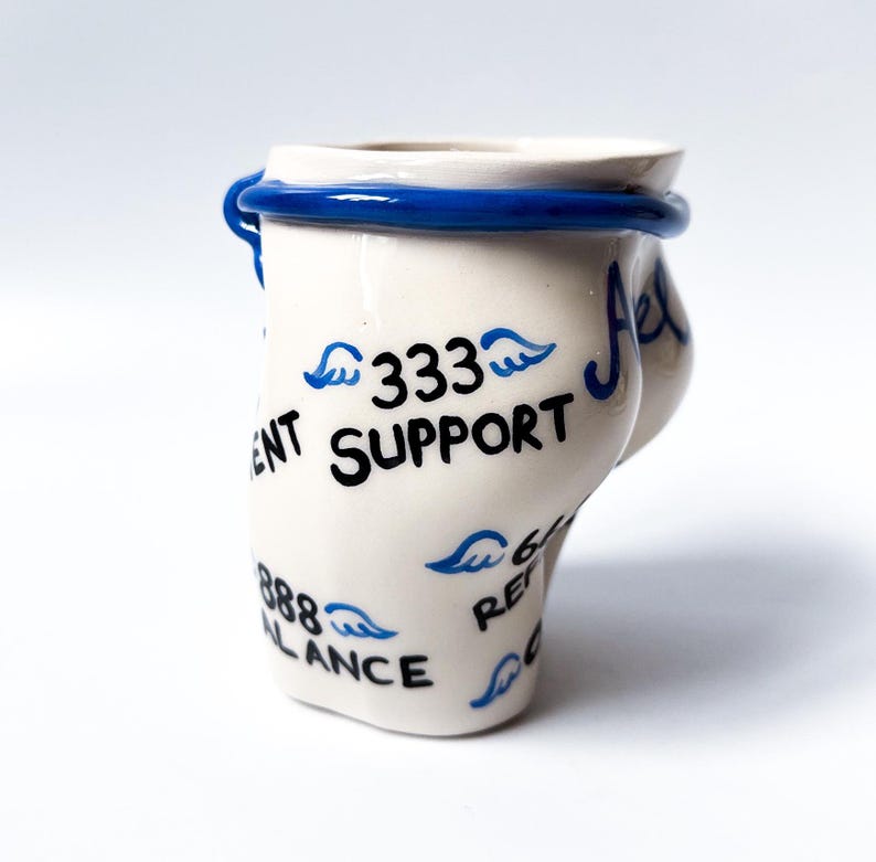 May include: White ceramic mug with blue trim and black writing. The writing includes "333 Support", "888 Balance", and "666 Refer".