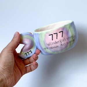 May include: A colorful ceramic mug with a swirl design and the text "777 Wonderful things are about to happen".