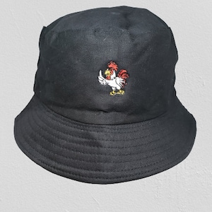May include: Black bucket hat with a detailed embroidered rooster design in red, white, and yellow. The hat has a wide brim and a classic, casual style, suitable for various outdoor activities.