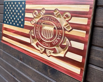 May include: A wooden American flag with the United States Coast Guard emblem in the center. The emblem is carved in relief and features an anchor, a shield, and the words "United States Coast Guard". The flag is painted in red, white, and blue.
