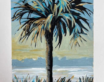 May include: An original acrylic painting of a palm tree against a blue sky and ocean. The palm tree has black, gold, and blue leaves. The painting has a white border and is signed in the bottom right corner.