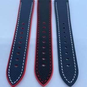 Puede incluir: Tres correas de reloj con una base de goma azul oscuro y costuras contrastantes. Una correa tiene costuras rojas, otra tiene costuras blancas y otra tiene costuras rojas y blancas.