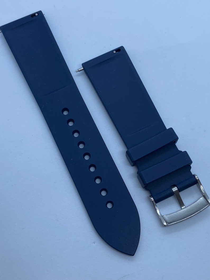 May include: A pair of dark blue silicone watch straps with a silver buckle. The straps are designed for a watch with a 22mm lug width.