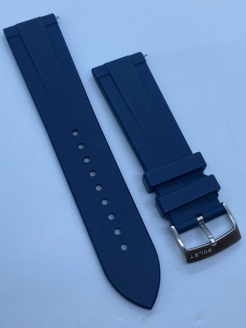 May include: A dark blue silicone watch strap with a silver buckle that says "GOLDSKY".