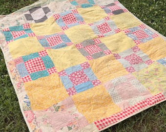 Colcha de los años 30 en color amarillo con estampado floral de sacos de pienso y cuadros vichy rojos.