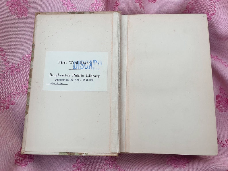May include: An open book with aged, off-white pages. The left page features a label from the "First Ward Branch" of the Binghamton Public Library, marked "DISCARD". The book is presented by Mrs. Stiffey.