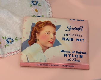 Puede incluir: Un paquete vintage de redecilla invisible Sessions en color marrón oscuro, con la ilustración de una persona con el cabello peinado. El empaque rectangular rosa incluye el texto: Sessions INVISIBLE HAIR NET Woven of DuPont NYLON with Elastic GUARANTEED - DURABLE - DEPENDABLE.