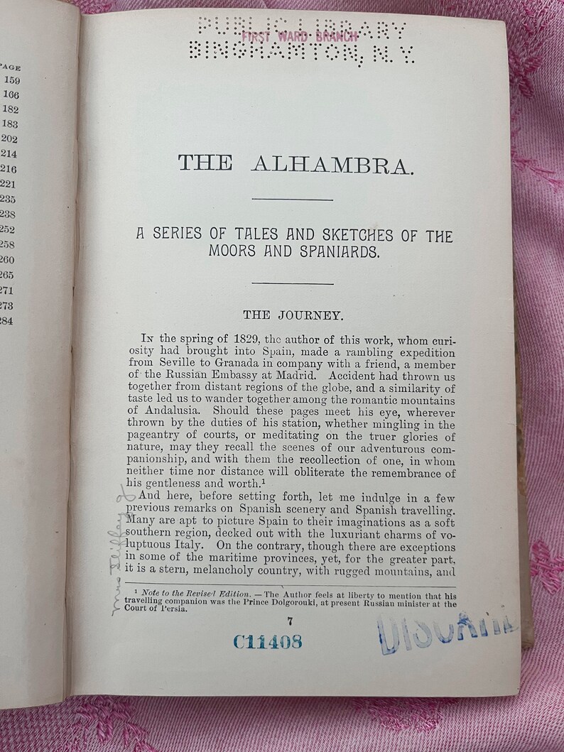 May include: Open book page with text titled "THE ALHAMBRA" and "A SERIES OF TALES AND SKETCHES OF THE MOORS AND SPANIARDS." The page has a list of numbers on the left and a stamp that says "PUBLIC LIBRARY BINGHAMTON, N.Y."