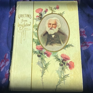 Op de afbeelding: Vintage ansichtkaart met de tekst "Greetings from Longfellow" en een illustratie van een man met een witte baard in een ovale lijst. De ansichtkaart heeft distel illustraties in rood en groen op een crèmekleurige achtergrond.