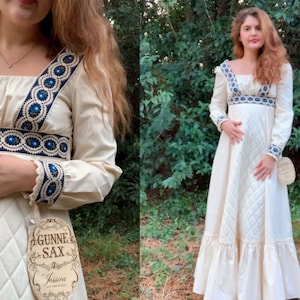 Puede incluir: Vestido largo color crema con escote cuadrado y mangas largas. El vestido presenta un ribete bordado azul y blanco a lo largo del escote, la cintura y los pu&ntilde;os. La falda tiene un patr&oacute;n acolchado y un dobladillo con volantes. La etiqueta dice "Gunne Sax" y "Jessica San Francisco."