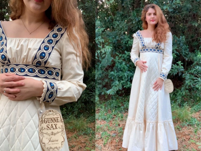 Puede incluir: Vestido largo color crema con escote cuadrado y mangas largas. El vestido presenta un ribete bordado azul y blanco a lo largo del escote, la cintura y los pu&ntilde;os. La falda tiene un patr&oacute;n acolchado y un dobladillo con volantes. La etiqueta dice "Gunne Sax" y "Jessica San Francisco."
