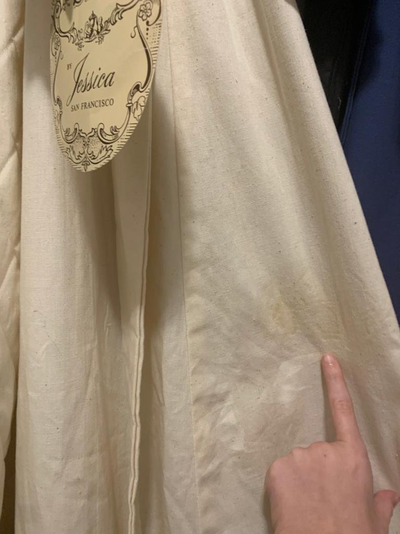 Puede incluir: Tela de color crema con una etiqueta que dice "by Jessica San Francisco". La tela parece ser un material natural, posiblemente lino o algod&oacute;n, con textura visible y algo de decoloraci&oacute;n. La etiqueta tiene un dise&ntilde;o ornamentado.