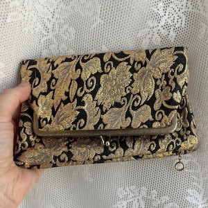 Cartera de mano plegable en dorado metálico y negro de los años 70 con compartimentos superiores e inferiores