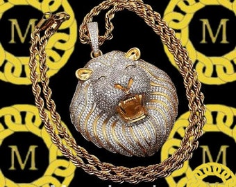 May include: A gold chain necklace with a large, diamond-encrusted lion head pendant. The pendant is detailed with a roaring expression and a gold mane.