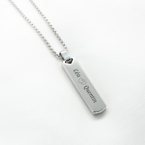 Peut inclure: Collier en argent avec un pendentif rectangulaire gravé des noms "Léa" et "Quentin" séparés par un symbole de cœur.