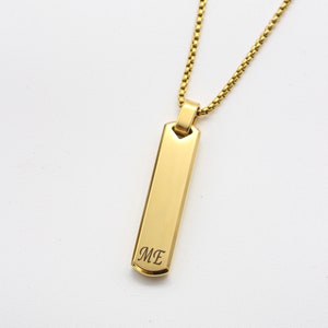 Peut inclure: Collier en chaîne dorée avec un pendentif en forme de barre dorée gravé des lettres "ME".