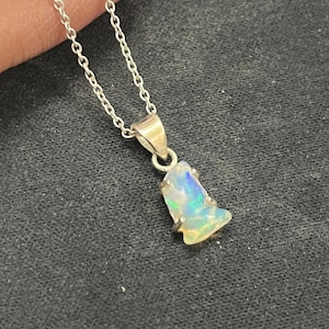 Peut inclure: Un collier en argent avec un pendentif en opale brute irisée.